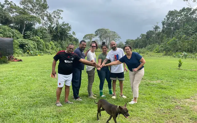 The planting group standing together on the grassy plot in Saramacca, with a dog in front